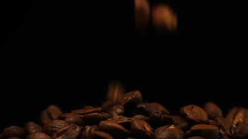 Zeitlupe fallender gerösteter Kaffeebohnen. Bio-Kaffeesamen.