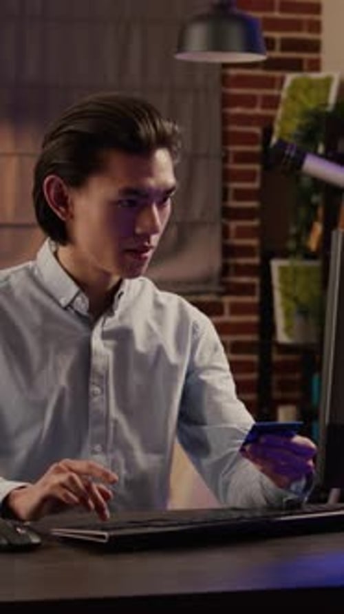 Young Adult Uses Credit Card on Computer at Desk