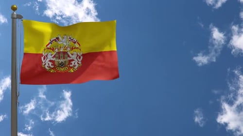 Waving Flag with Ornate Coat of Arms Against Blue Sky