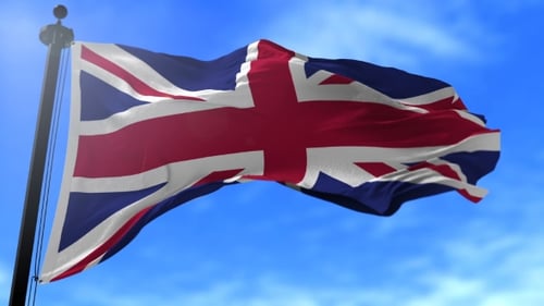 Waving Union Jack Flag Against Blue Sky