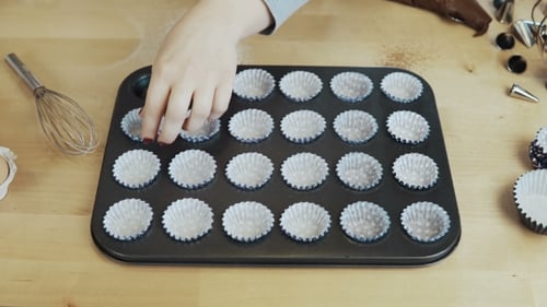 View of Female Hand Putting the Wrappers Paper Cups Into the Baking Dish Woman Cooking Cupcakes
