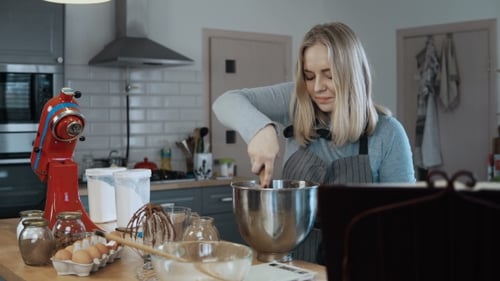 Junge schöne Frau mischt die Zutaten in einer Schüssel, bereitet Teig zum Backen der blonden Frau vor