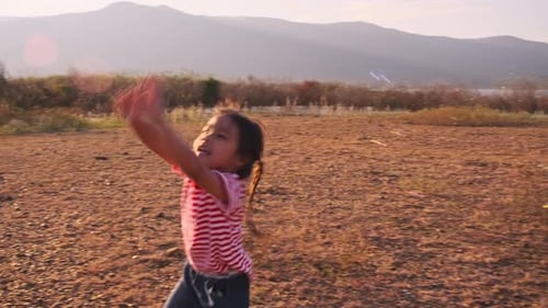 Cute little girl playing with soap bubbles in the summer park at sunset.