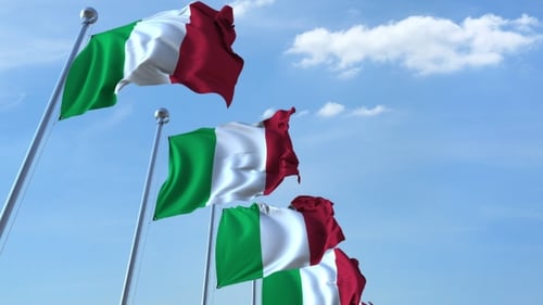 Multiple Italian Flags Waving in the Wind Against Blue Sky