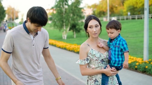 Father, Mother and Their Little Son Are Walking in a City Park in Summer, Talking, Smiling
