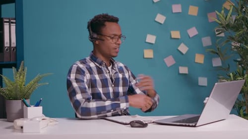 Young Man Talking with Client on Phone Call at Helpline Call Center