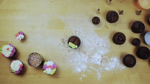 Weibliche Hände zum Dekorieren der Schokoladen-Cupcakes Junge Frau mit dem Spritzbeutel für