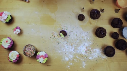 Top View of Chocolate Cupcakes on the Table. Young Woman Decorating Muffins with Colored Cream From