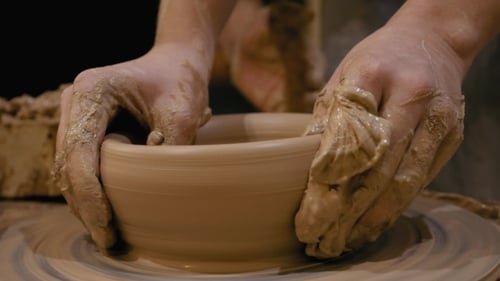 Hands shaping clay on spinning pottery wheel