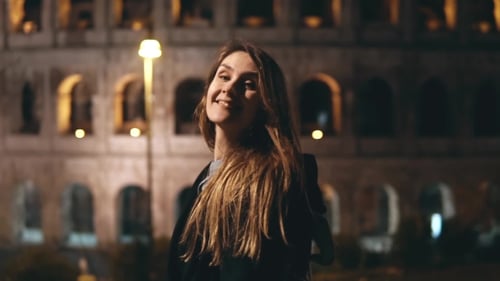 Young Beautiful Woman Standing Near the Colosseum in Rome, Italy, Looks Back in Camera and Smiling