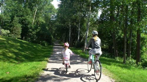 Mãe e filha andam de bicicleta no parque