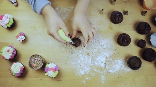 Ansicht von Frauenhänden, die die Schokoladen-Cupcakes schmücken