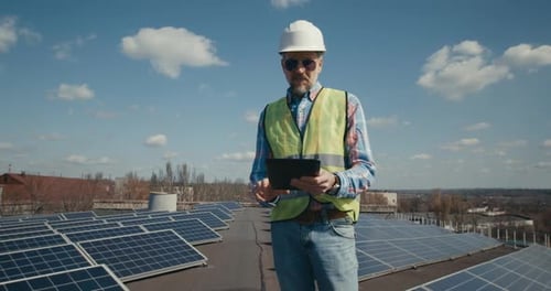 Engineer Using Tablet Between Solar Panels
