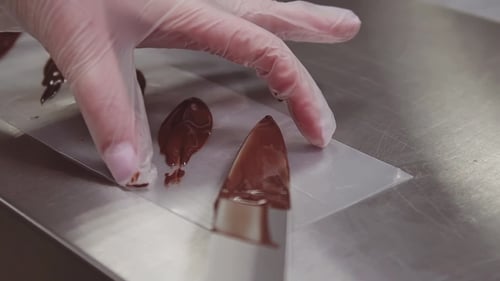 Gloved Hand Dollops Chocolate onto Parchment Paper
