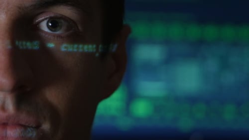Portrait of Man Programmer Hacker with Green Code Characters Reflect on His Face with a Computer