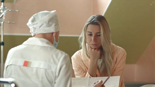 Young Female Doctor with Female Patient Talking in Hospital Room