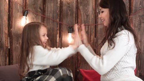 Happy Mother and Daughter Playing Clapping Game on Christmas Eve