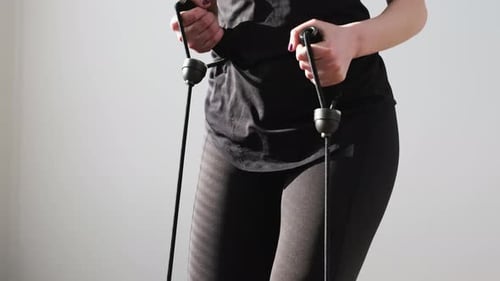 Mulher com roupa esportiva preta fazendo exercícios usando o expansor no stepper