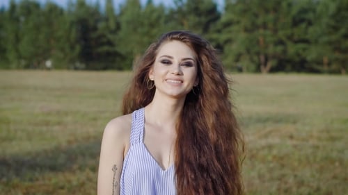 Young and Beautiful Woman Is Happily Walking Across the Field, Smiling, Laughing