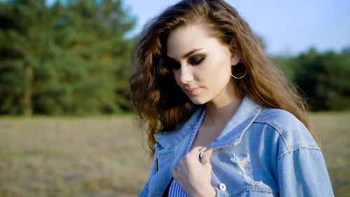 Young Adorable Woman Goes for a Quite, Long Stroll in the Field Wearing Jeans Jacket