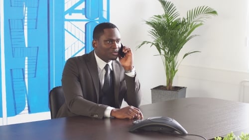 Young Black Businessman Uses Phone in Office