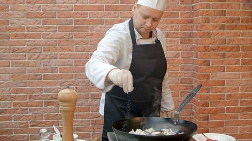 Chef Adding Spices to Dish in Frying Pan
