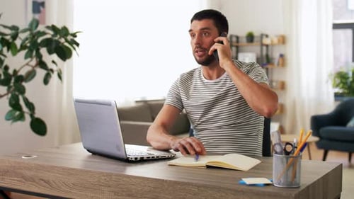 Man with Laptop Calling on Phone at Home Office