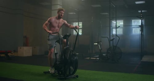 Young Man Using Exercise Bike at the Gym. Fitness Male Using Air Bike for Cardio Workout at Gym