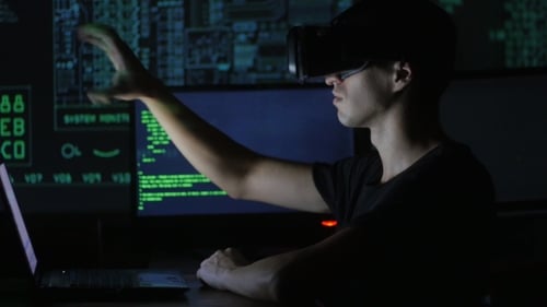 Young Man Uses VR Headset with Computer Code