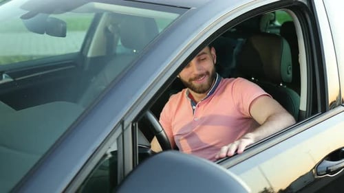 Smiling Man Sits in a Car in Daytime