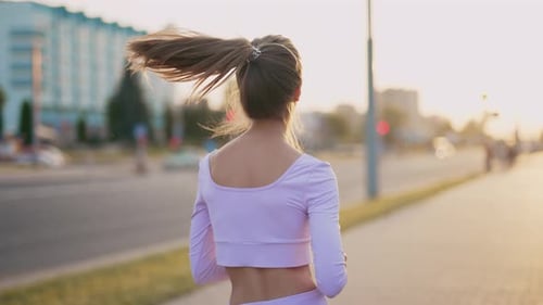 A Young Woman Runner is Training in the Summer Within a City