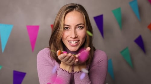 Happy Woman Blows Colourful Confetti to the Camera