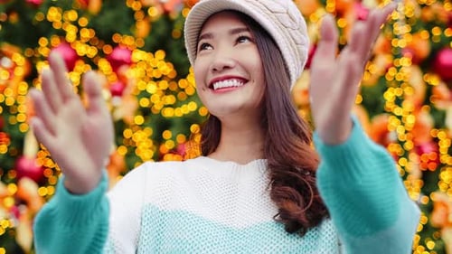 Happy Young Woman Waves Before Christmas Tree