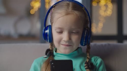 Little Girl with Headphones Watching Smartphone