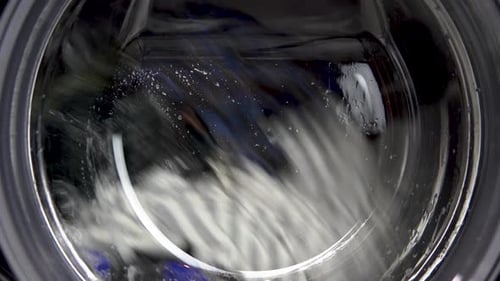 The Washing Machine Is Working. A Washing Machine Spins a Drum Filled with Clothes. Drum Close Up