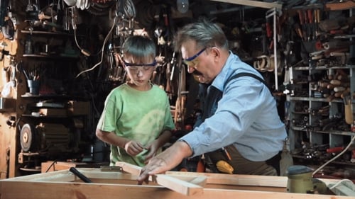Carpenter with Grandson Working in Workshop
