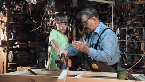 Child Learning Woodworking with Adult Supervision in Workshop