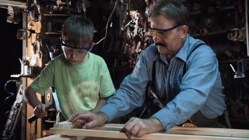 Grandfather and Child Woodworking Together in Workshop
