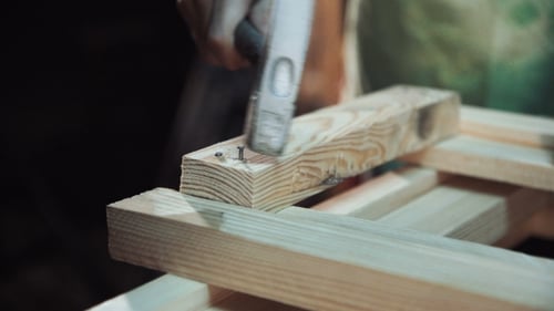 Carpenter Constructing Wooden Frame with Hammer