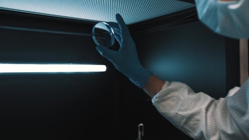 Scientist Manages Lenses in Metal Lighted Box at Laboratory