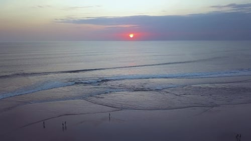 Tranquil Beach Sunset with Gentle Waves and People