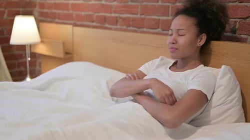 African Woman Feeling Worried While Sitting in Bed