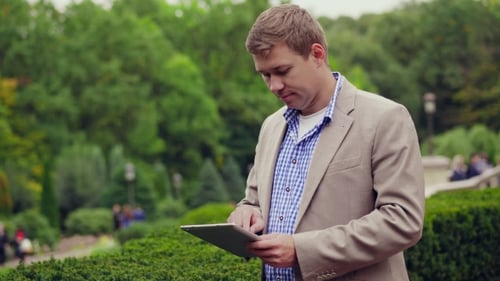 Young Man With Tablet Computer In Park