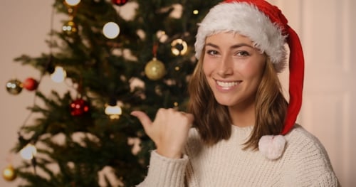 Woman Wearing Santa Hat Standing by Christmas Tree