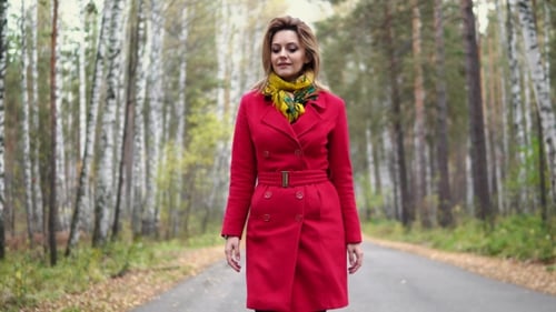 Attractive Young Woman Walking in the Autumn Park. the Girl in the Red Coat and Scarf