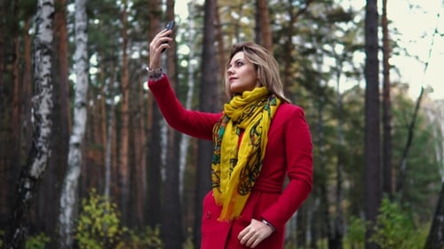 Young Woman in a Red Coat Walking Along an Autumn Park. Beautiful Girl Enjoying a Warm Autumn