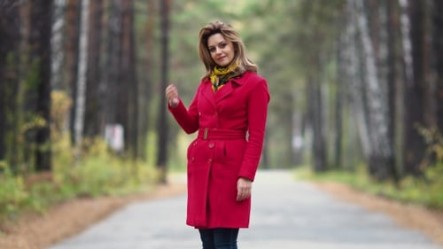 Portrait of a Young Woman in an Autumn Park. Beautiful Girl in Red Coat Posing and Smiling at the