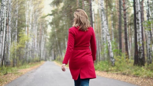 Young Woman Walking in Autumn Park, Playfully Turns and Looks at the Camera. Attractive Girl in