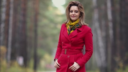 Portrait of a Beautiful Young Woman on a Background of Autumn Forest. Girl in Red Coat Smiles and