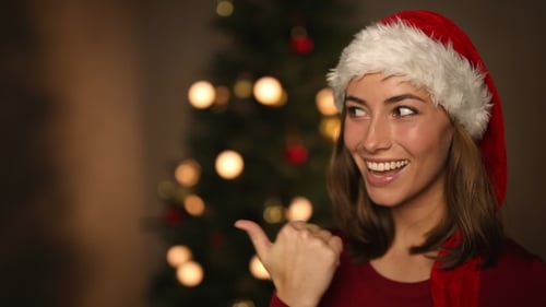 Smiling Woman Wearing Santa Hat Points Sideways